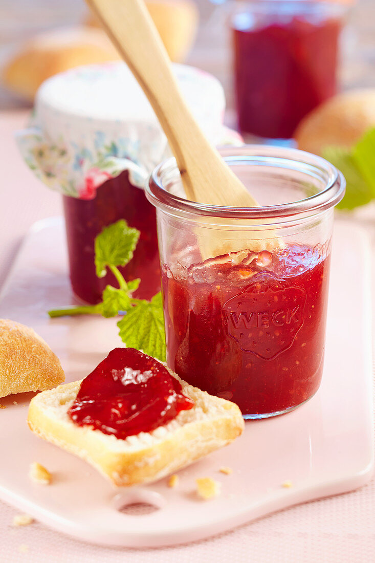 Mango, raspberry and strawberry jam in a jar and on a slice of bread