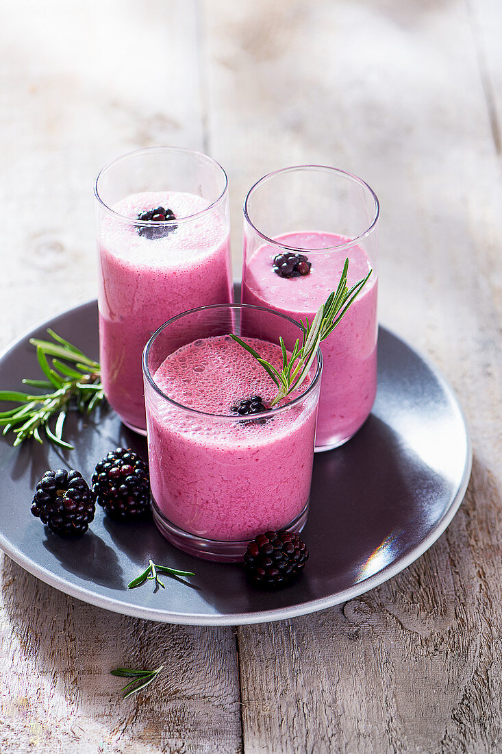 Blackberry drinking yoghurt in glasses with fresh rosemary
