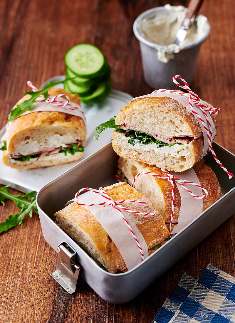 Baguette-Sandwiches mit Leberkäse, Meerrettich, Frischkäse und Rucola in Lunchbox
