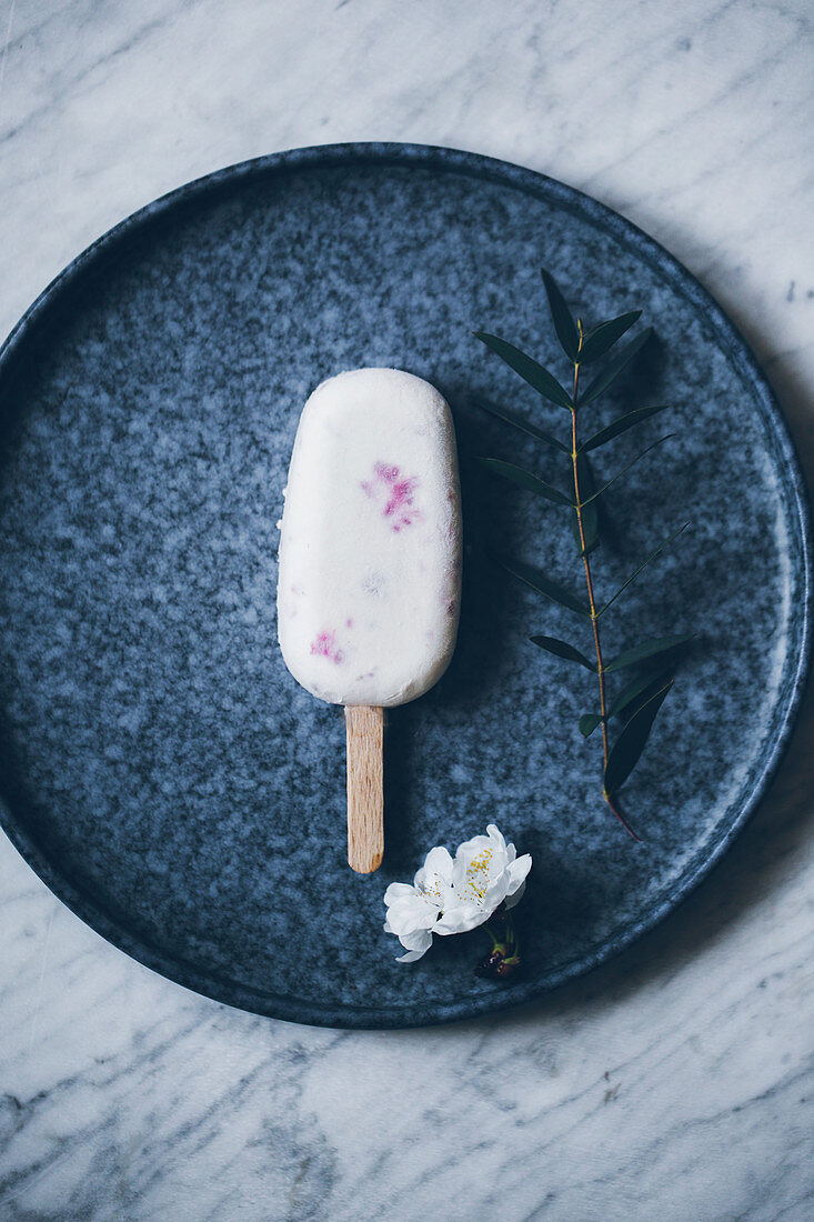 Stieleis mit Himbeeren auf Keramikteller