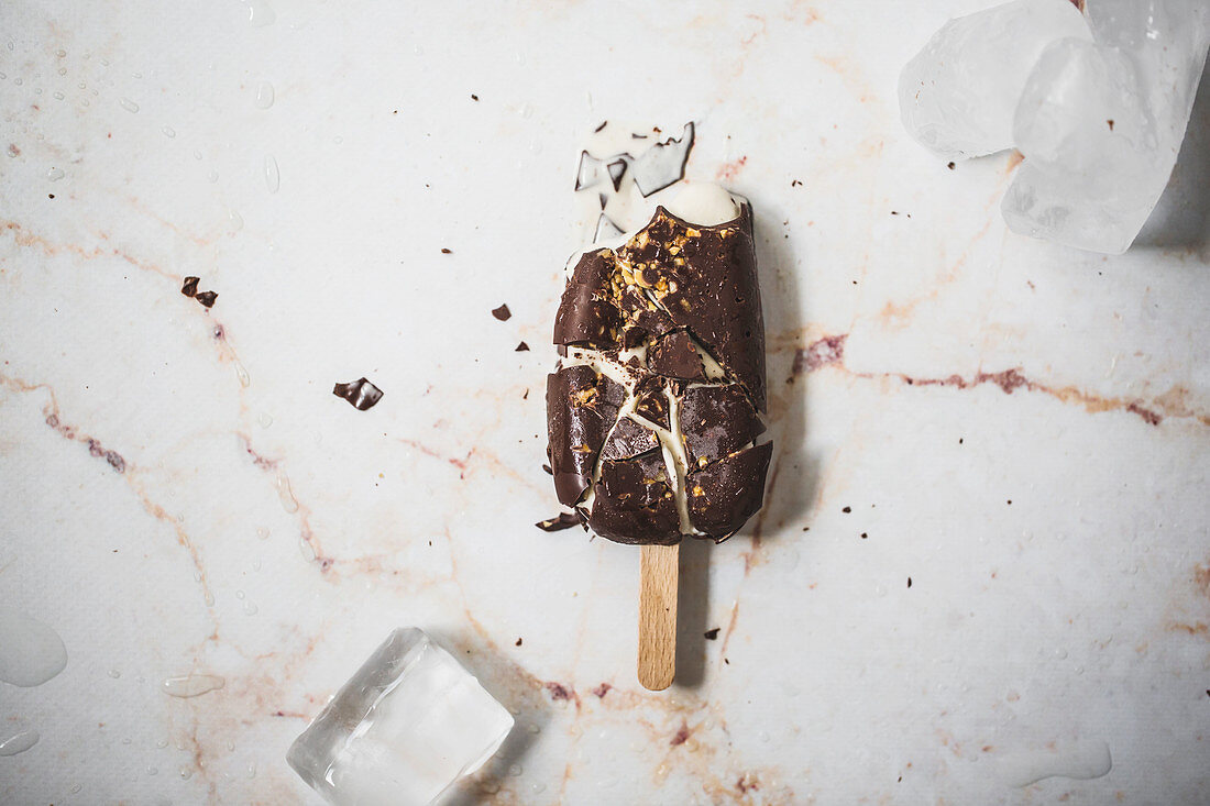 Crashed vanilla and chocolate ice cream popsicle on a marble surface