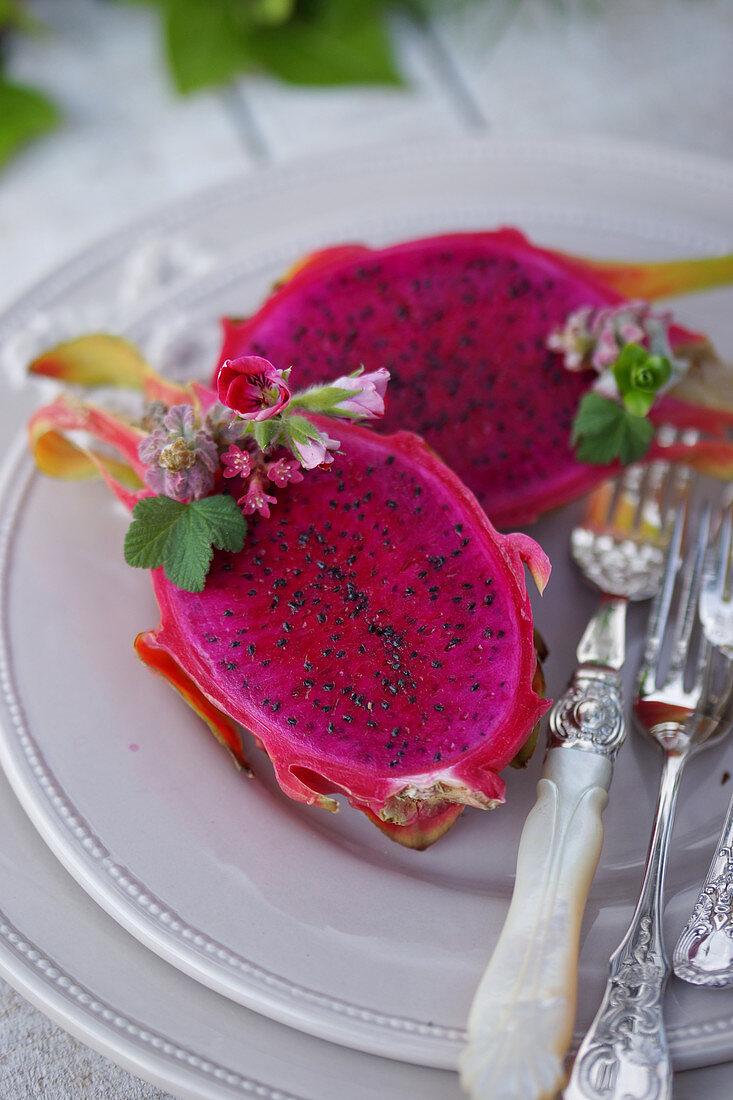 Halved dragon fruit with elegant silver cutlery on a plate