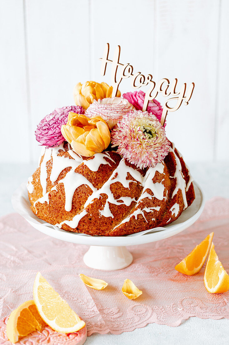 Orangen-Gugelhupf dekoriert mit Blüten und Schriftzug 'Hooray'