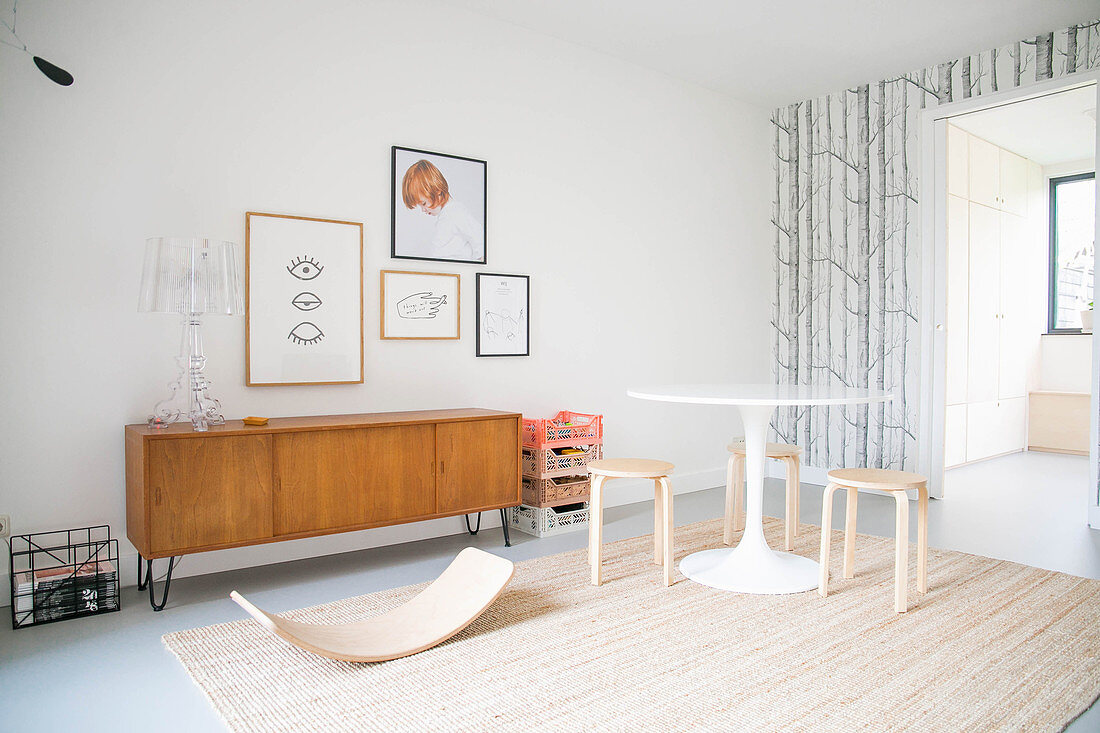 Baby bouncer, round table and retro sideboard in playroom