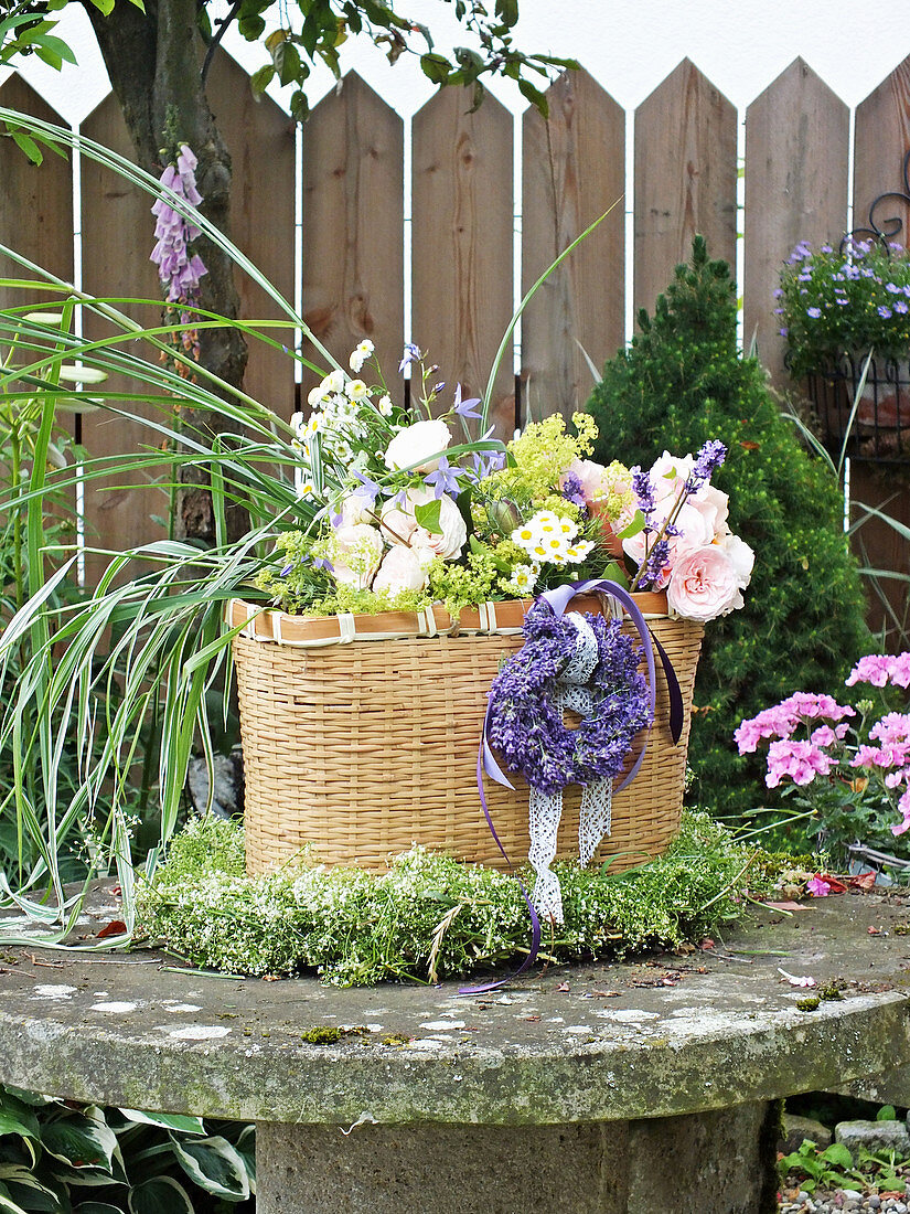 Summer bouquet of roses, grasses and lavender in basket in wreath of lavender