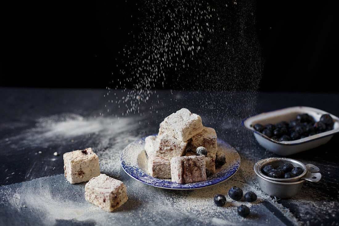 Blueberry marshmallows being dusted with icing sugar