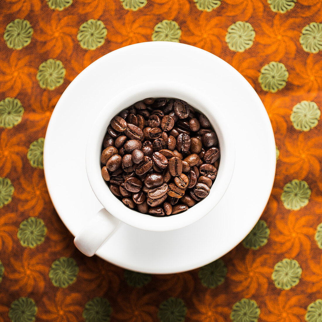 Kaffeebohnen in Kaffeetasse auf Stoffuntergrund