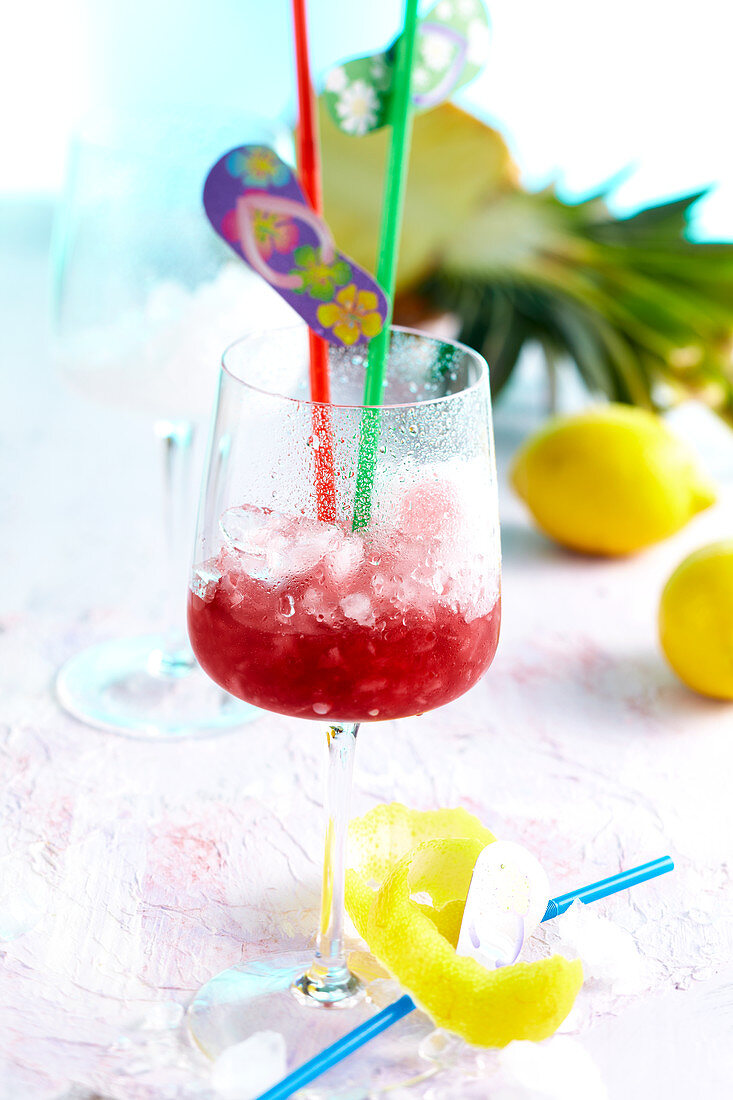 A mocktail in a wine glass with grenadine, sour cherries, lemon and pineapple