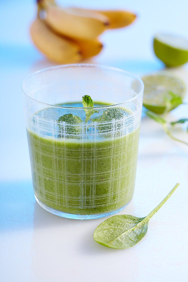 A green smoothie made with banana, apple, spinach, cucumber, ginger, lime and coconut milk