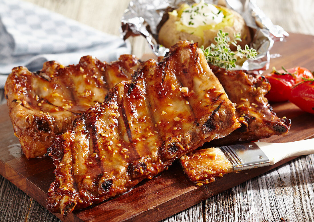 Gegrillte Spare Ribs mit Folienkartoffel auf Holzbrett