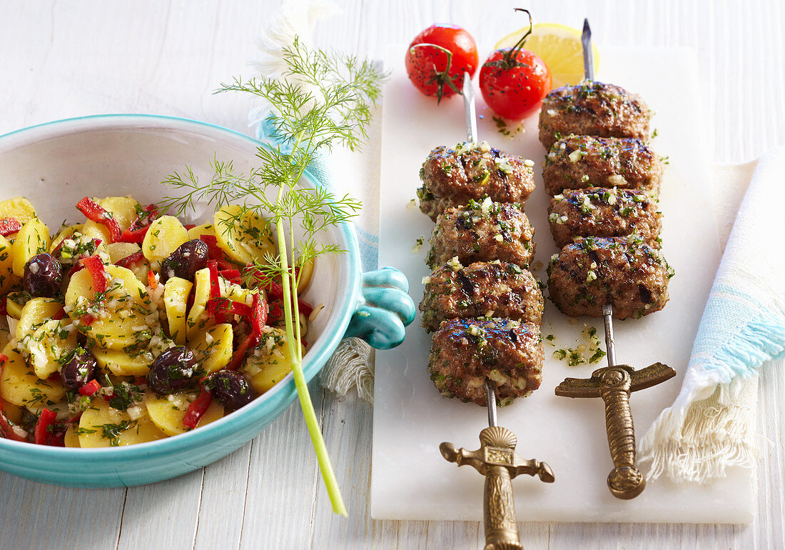 Gegrillte Gyros-Spiesse mit griechischem Kartoffelsalat mit Oliven, Tomate und Zitrone