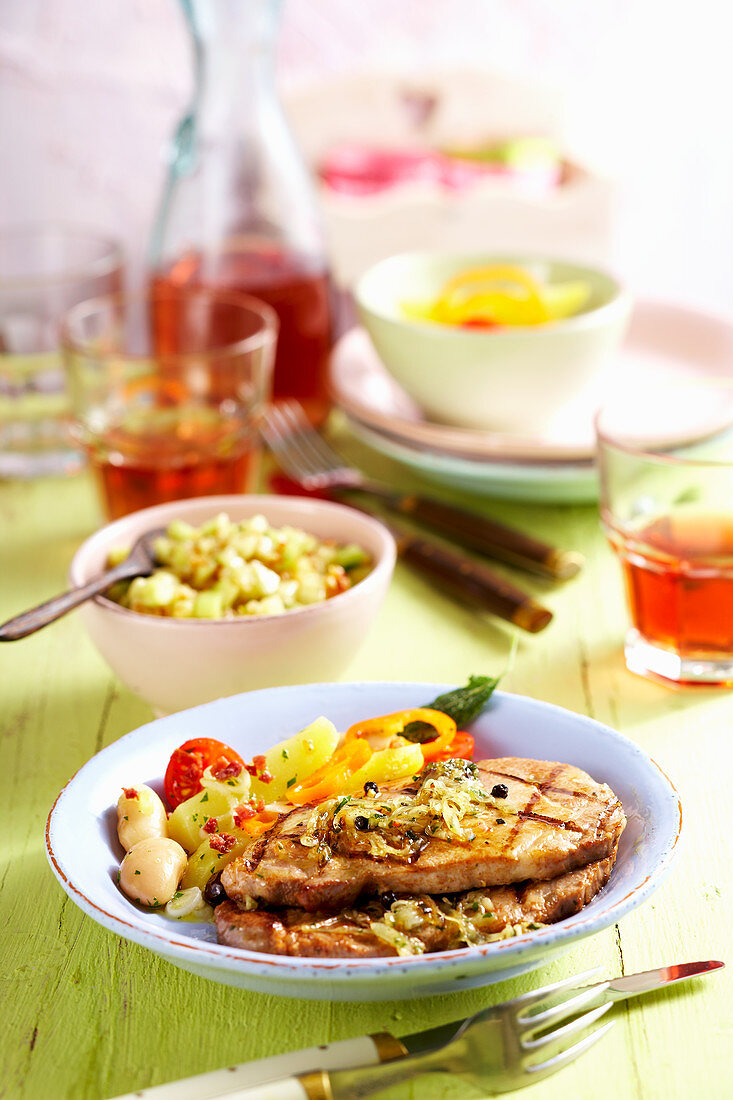Grilled marinated pork collar steaks with cucumber salsa, potato salad and white beans