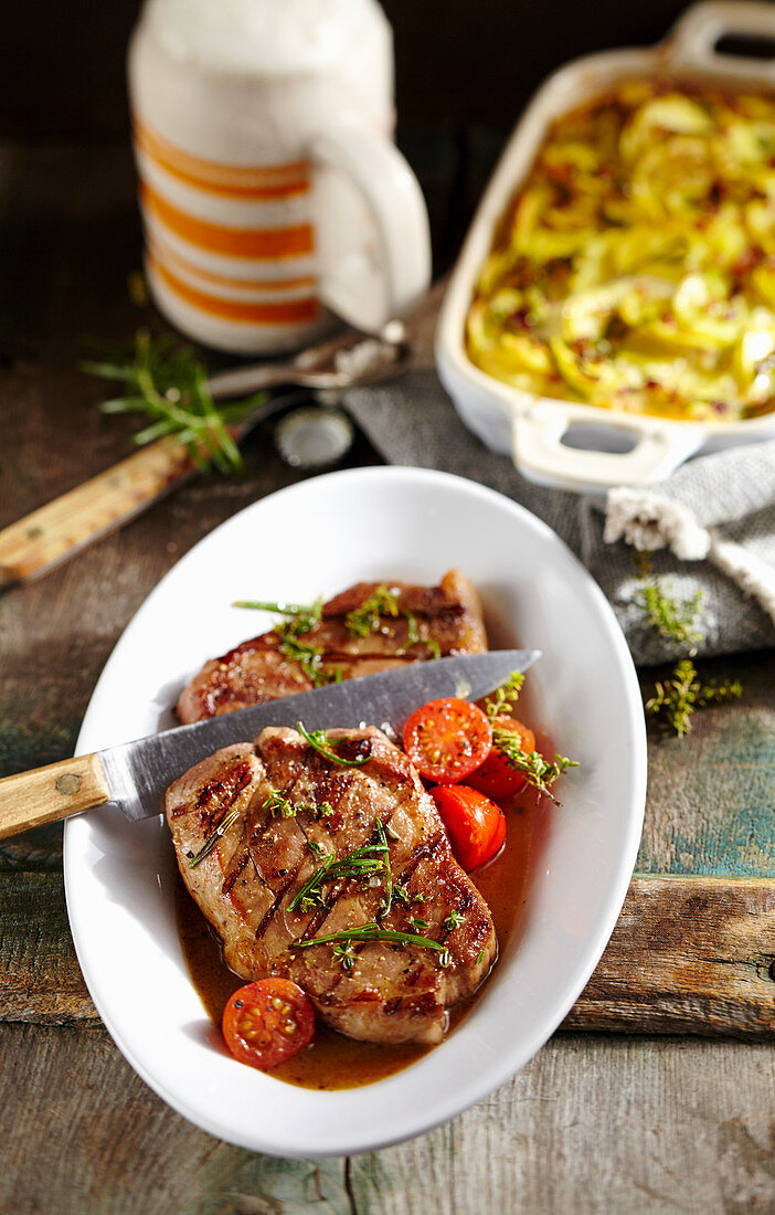 Grilled pork collar steaks in a beer marinade with a potato and beer gratin