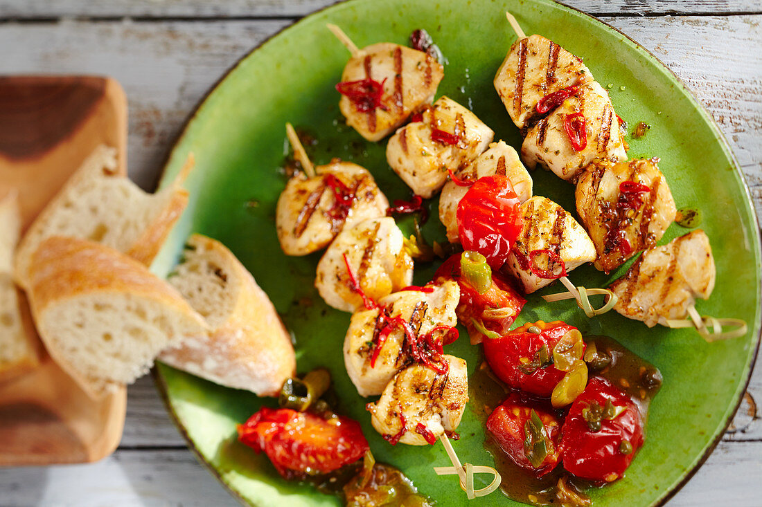 Grilled, marinated chicken skewers with a cherry tomato sauce and basil
