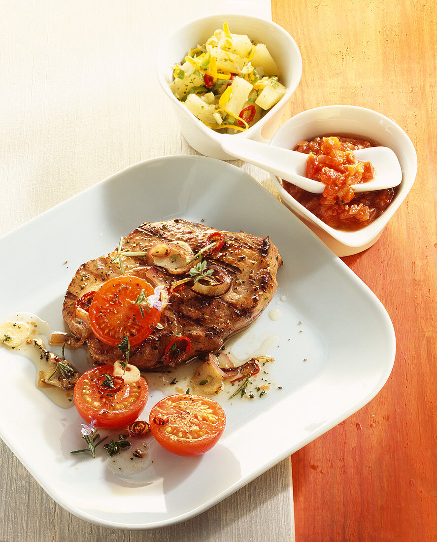 Grilled, marinated pork collar steak with tomato salsa and pineapple and chilli salsa