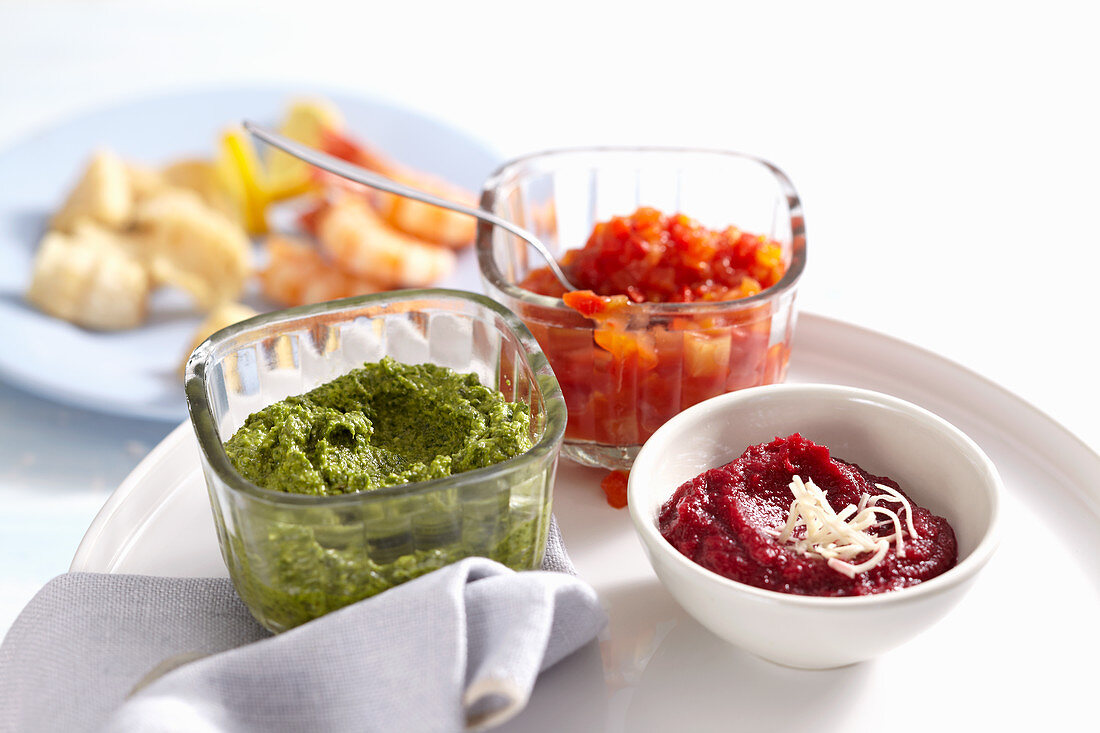 Bowls of various sauces for a fish fondue (exotic chutney, beetroot and horseradish dip, rocket and nut pesto)