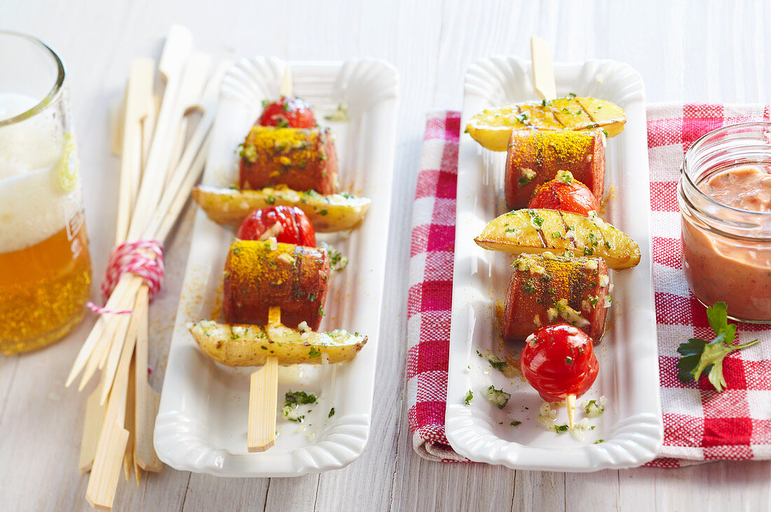 Grilled sausage and potato skewers with a tomato dip, curry and beer
