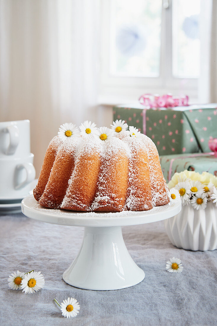 A lemon Bundt cake decorated with daisies for a birthday