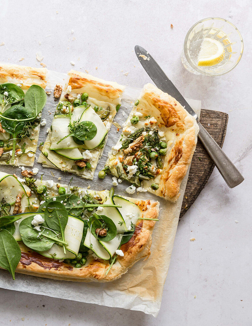 A pizza topped with green vegetables and nuts