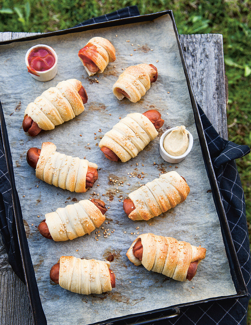 Sausages wrapped in pastry on a baking tray