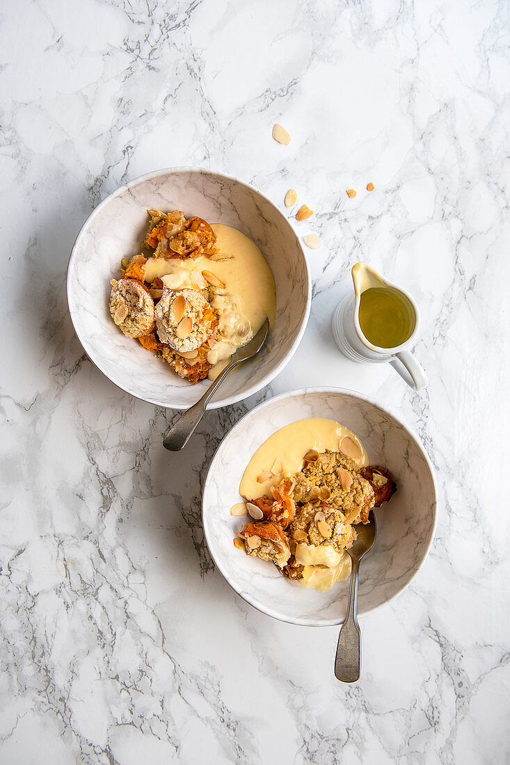 Apricot and almond crumble in serving bowls with custard