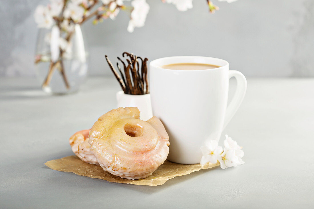 Vanilledonuts mit Zuckerguss und Tasse Kaffee