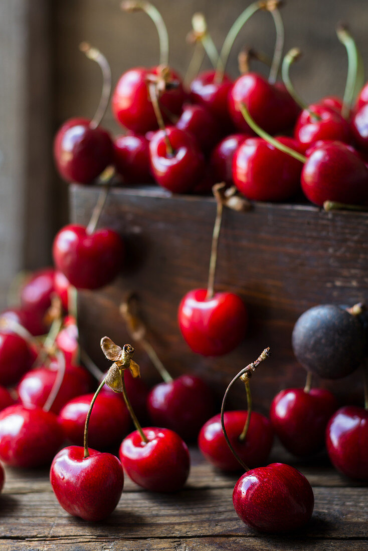 Cherries in a wooden crate and on a table