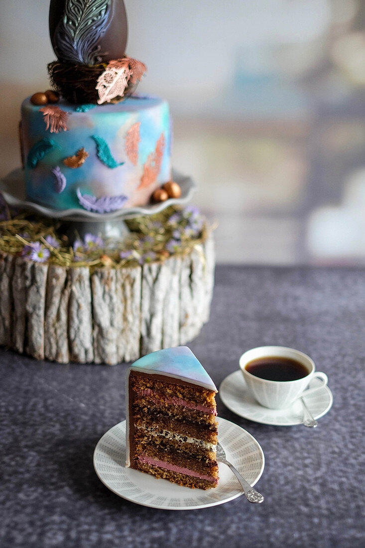 A slice of Easter cake topped with a peacock feather chocolate egg
