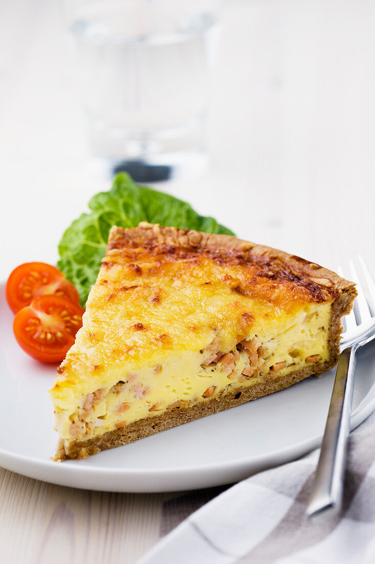 A slice of bacon tart with tomatoes and a lettuce leaf