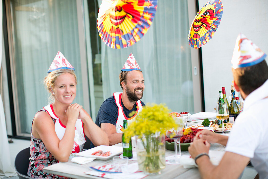 Fröhliche Menschen feiern das Flusskrebsfest an einem Tisch sitzend