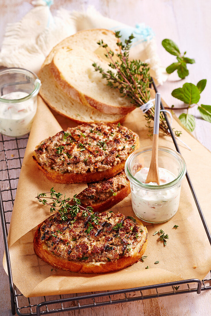 Slices of roasted Greek minced meat bread with feta cheese, herbs and a yoghurt and mint dip