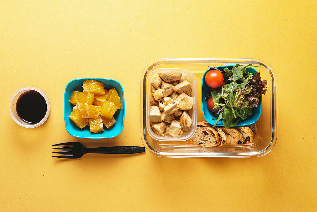 Gesunde Lunchbox mit Hähnchen, Salat und Orange