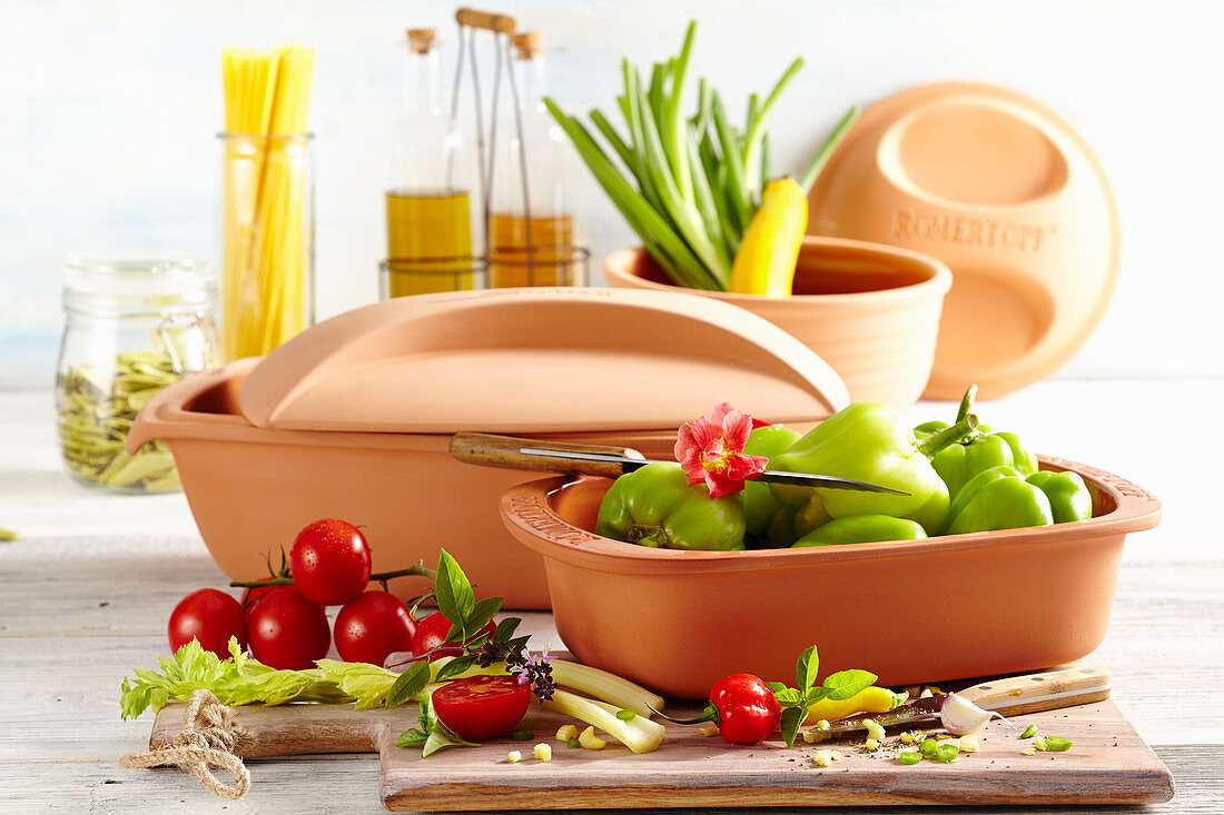 An arrangement of clay cooking dishes, vegetables and pasta