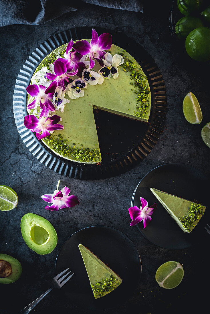 Avocado-Limetten-Cheesecake dekoriert mit Blüten und Pistazien
