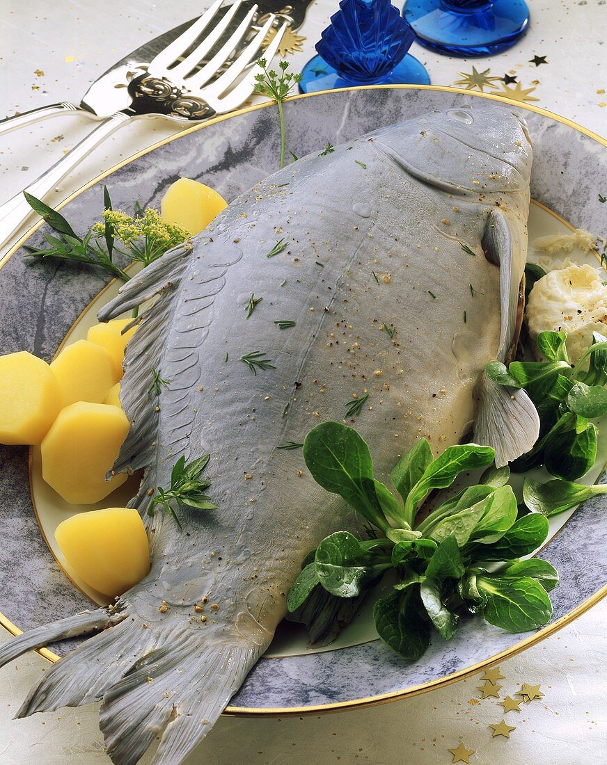 Carp cooked blue with boiled potatoes corn salad on plate