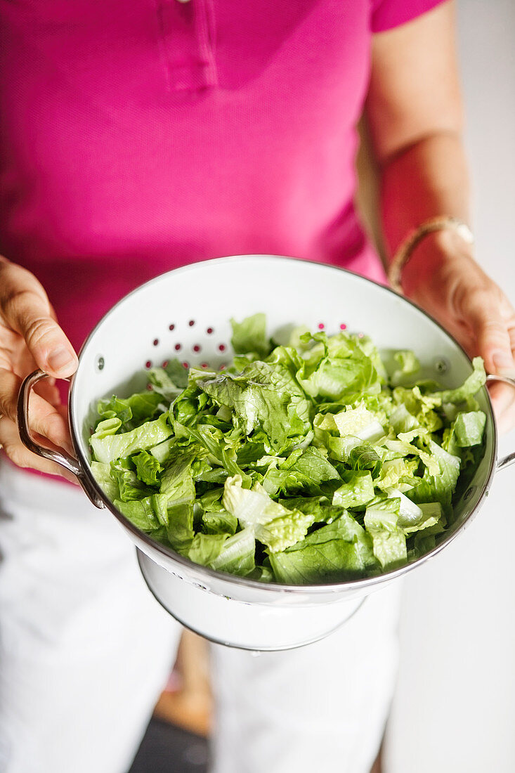 Woman holding colander with lettuce