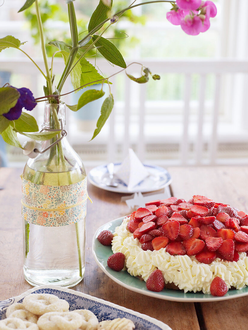 Erdbeertorte auf Kaffeetisch mit Blumendeko