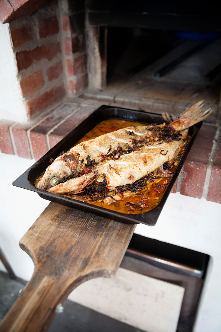 Baked fish in front of a brick oven