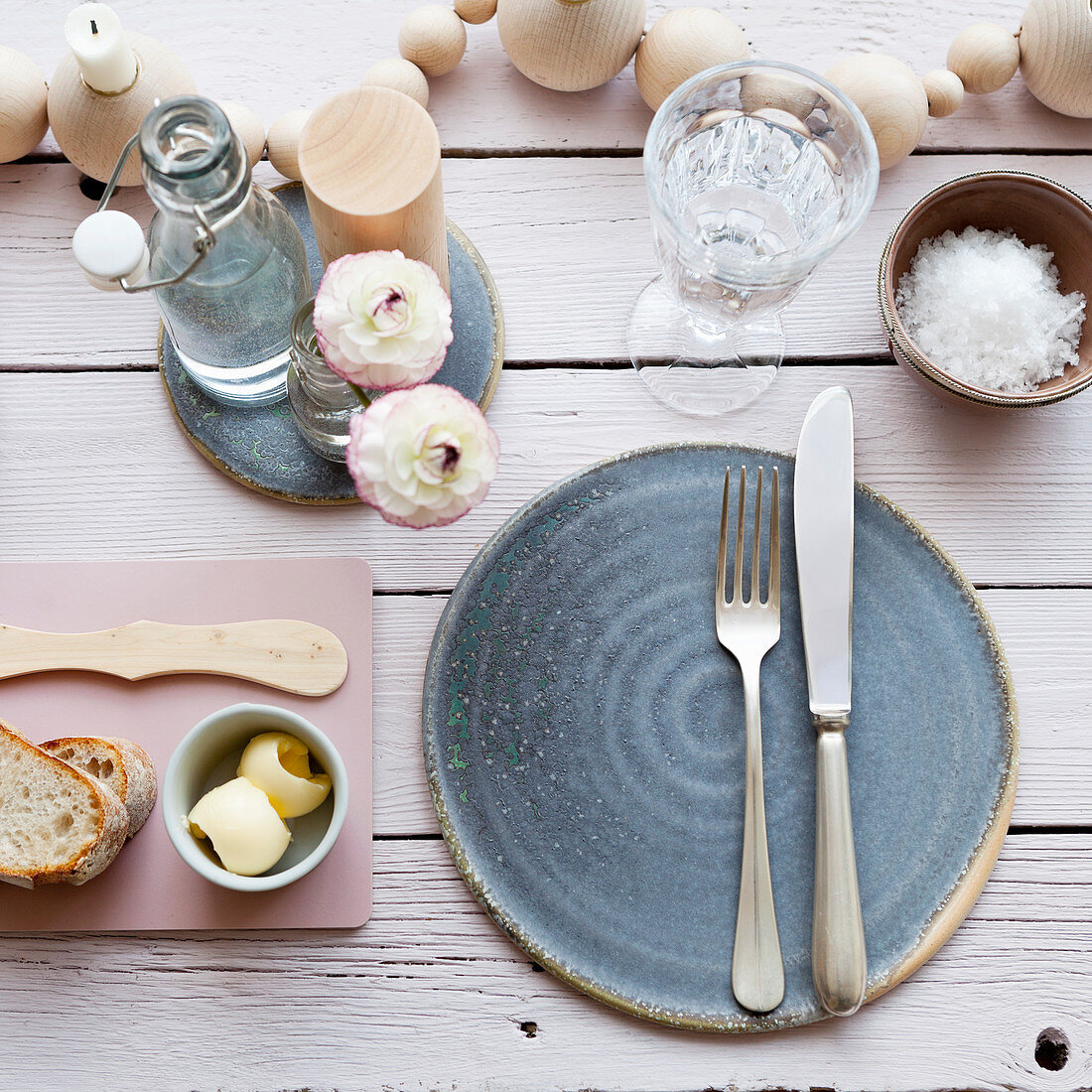 A place setting with a blue ceramic plate, butter, salt and bread