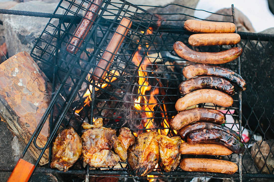 Cooking sausages and chicken on a campfire