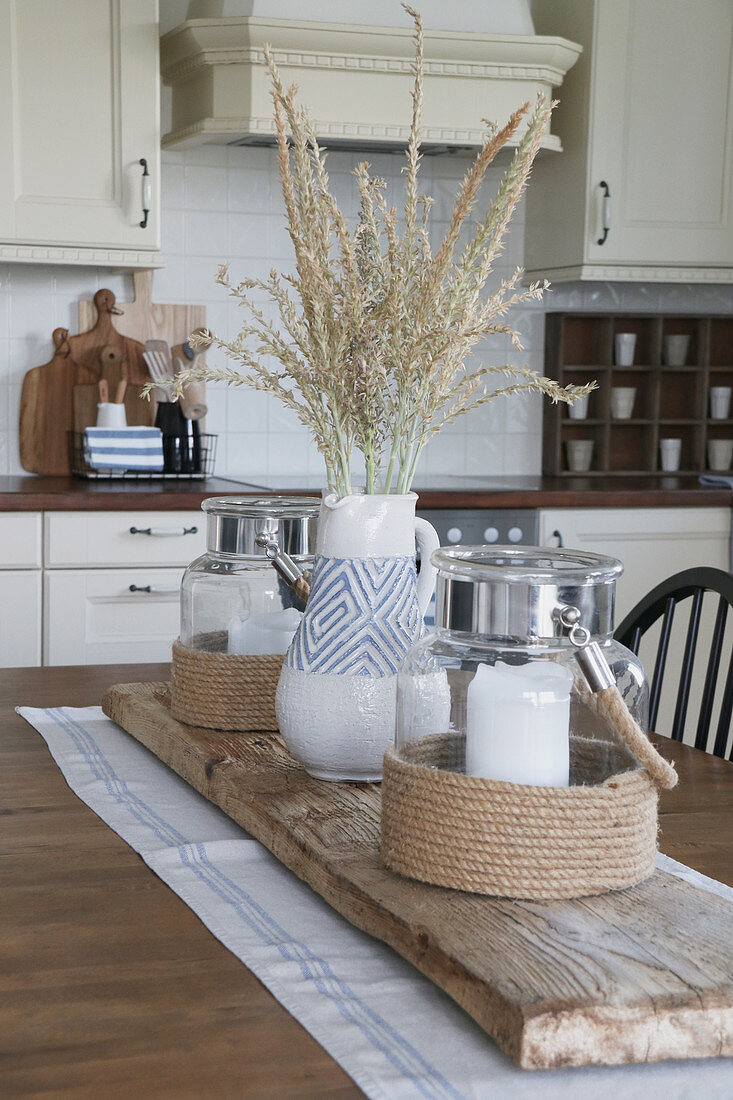 Summery arrangement of lantern and blue-and-white ceramic vase on driftwood board on kitchen table