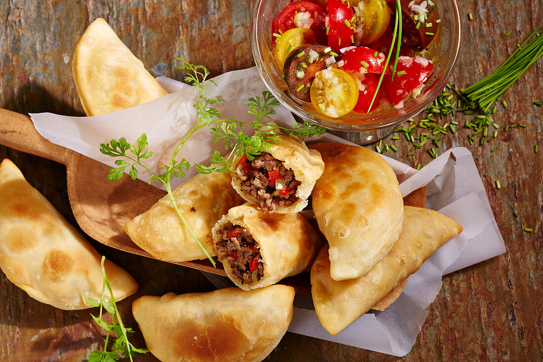 Baked chilean empanadas with beef filling and cherry tomato salad