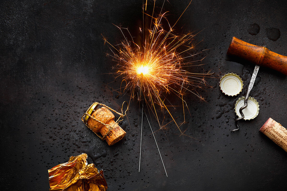 A symbolic image for New Year's Eve: sparklers, champagne, corks and bottle lids