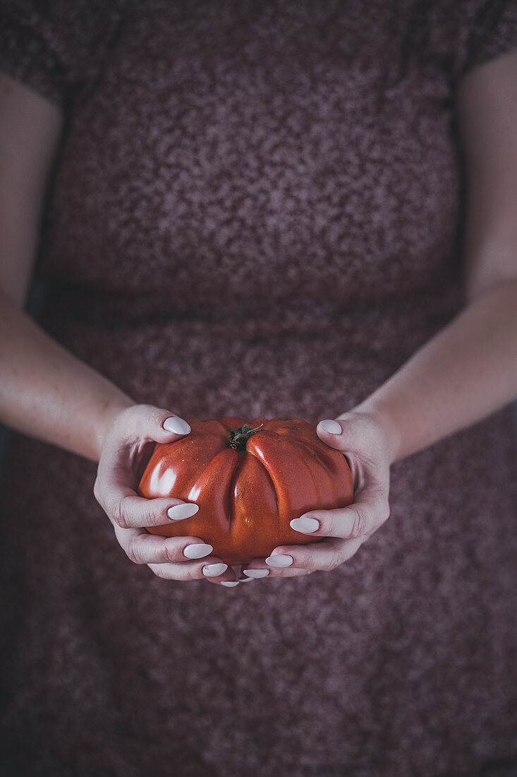Frau hält große Tomate
