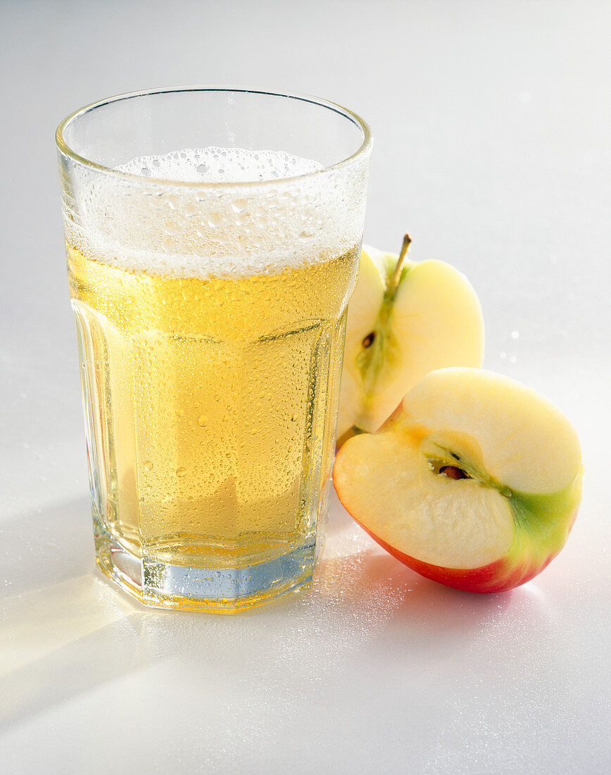A glass of apple juice spritzer with apple halves
