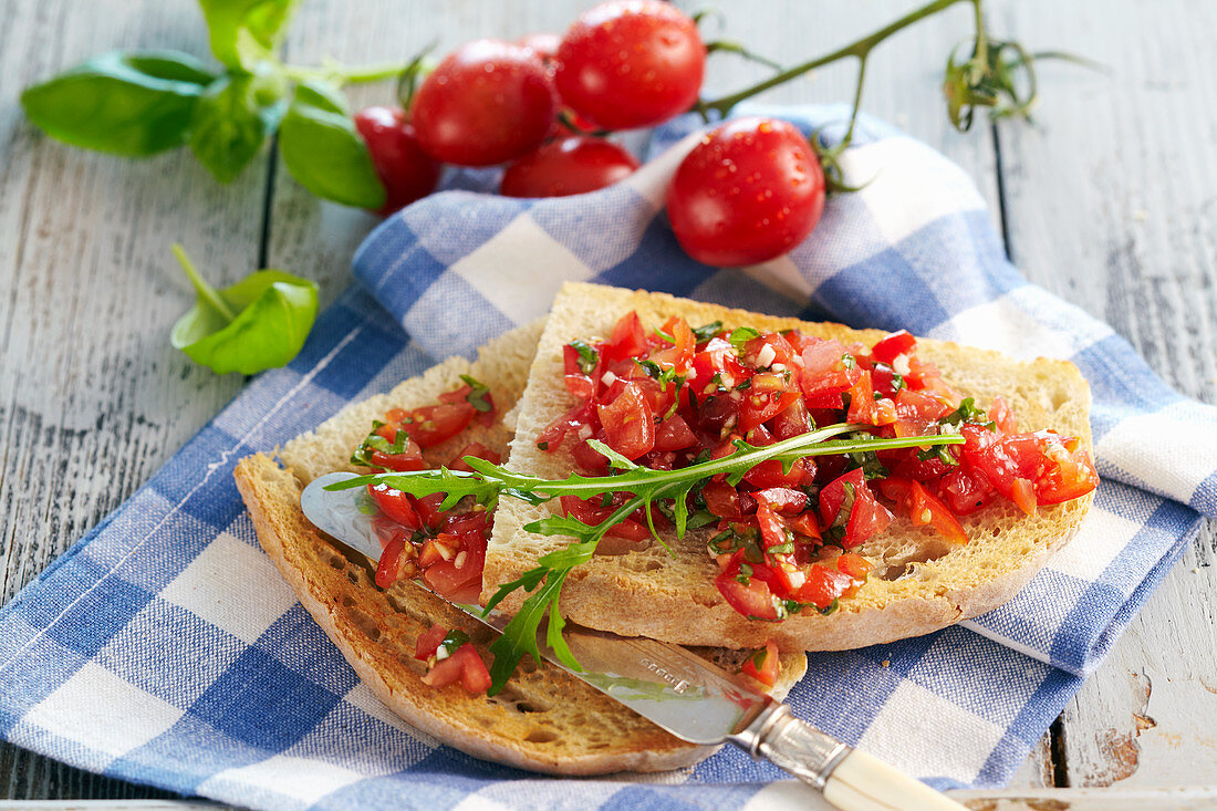 Classic bruschetta from Apulia with tomatoes, basil, olive oil, peperoncini and arugula
