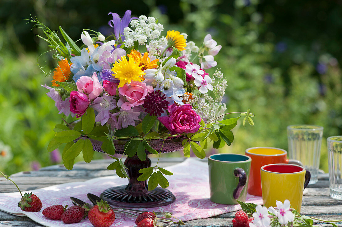 Buntes Blumengesteck auf Tortenplatte als Tischdekoration