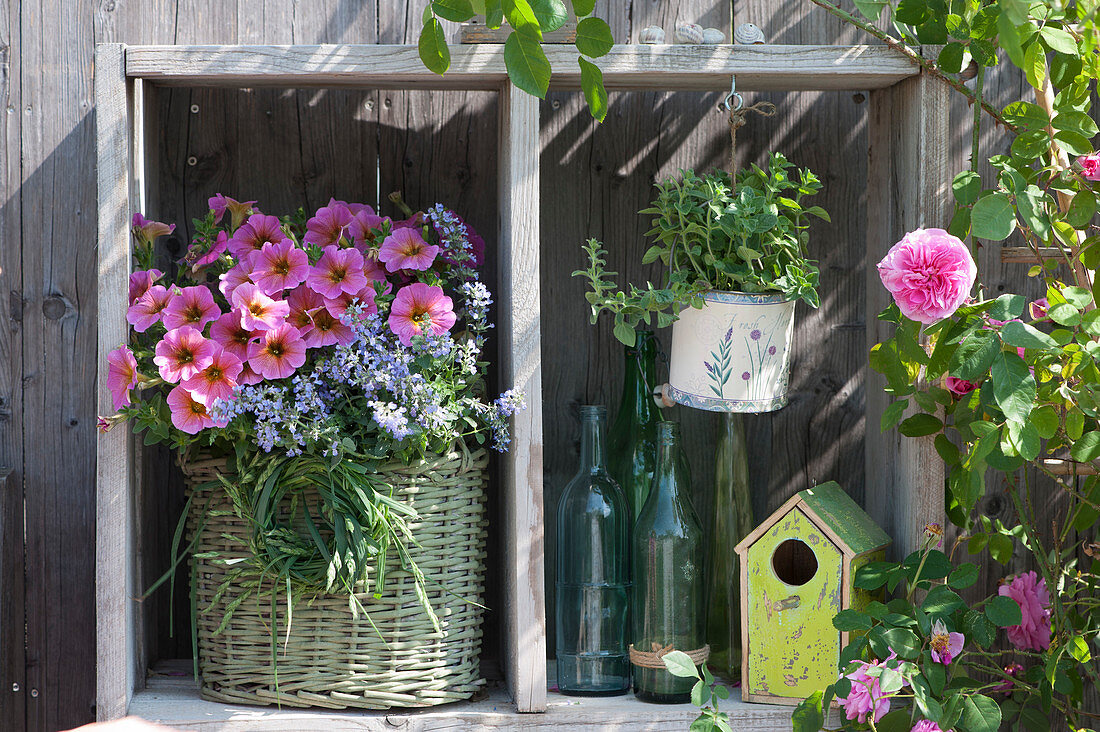 'Beautical Sunray Pink' Petunia and 'Cats Meow' catnip in the basket, grass wreath, bird house, and bottles as decorations with 'Gertrude Jekyll' rose blossoms.