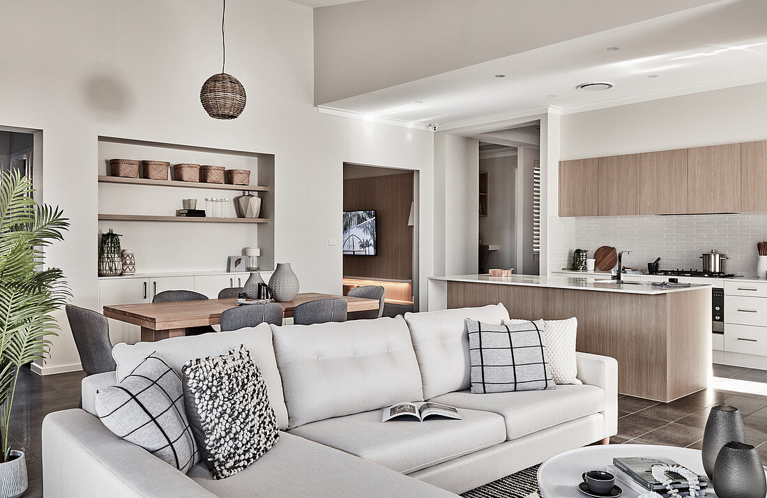 Pale sofa set with cushions and dining area and kitchen in background