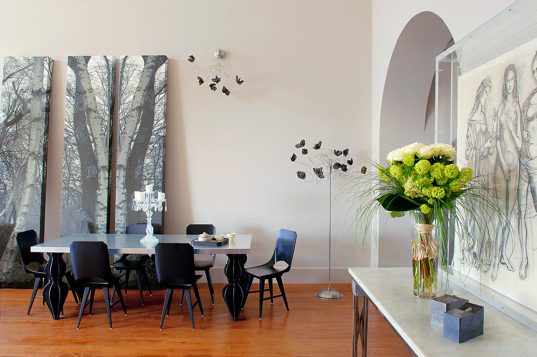 Flowers on console table, arched doorway and dining area in open-plan interior